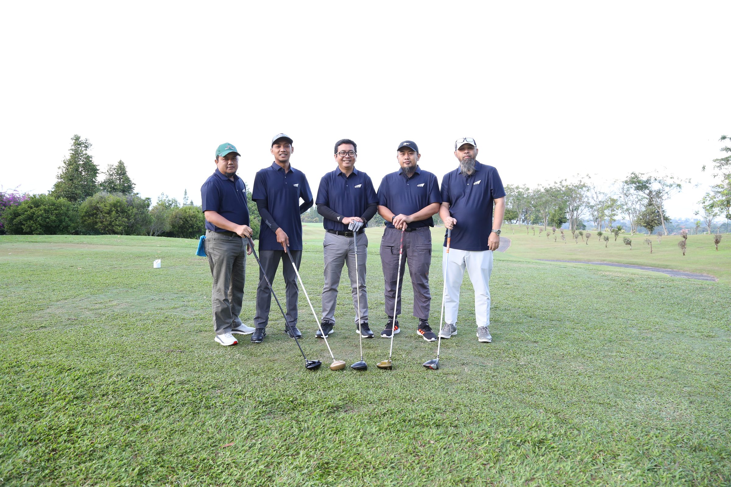 Lima peserta turnamen golf berpose dengan stik di area tee box